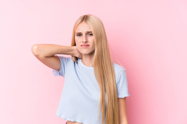 Mladá blondýna žena na růžovém pozadí trpí bolestí krku v důsledku sedavého životního stylu. - Fotografie, Obrázek
