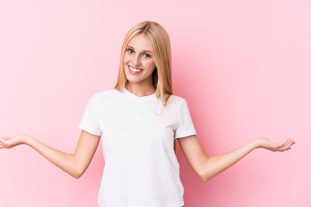 Young blonde woman on pink background showing a welcome expression. - Photo, Image