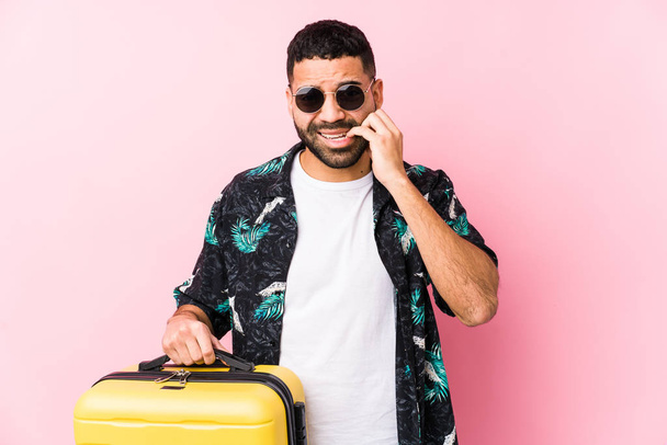 Jeune homme latino tenant une valise mordant les ongles, nerveux et très anxieux
. - Photo, image
