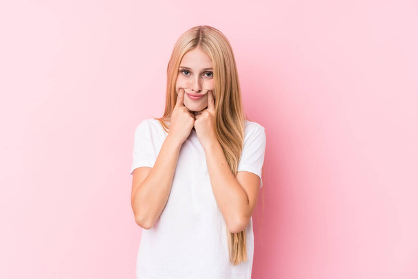 Young blonde woman on pink background doubting between two options. - Photo, Image
