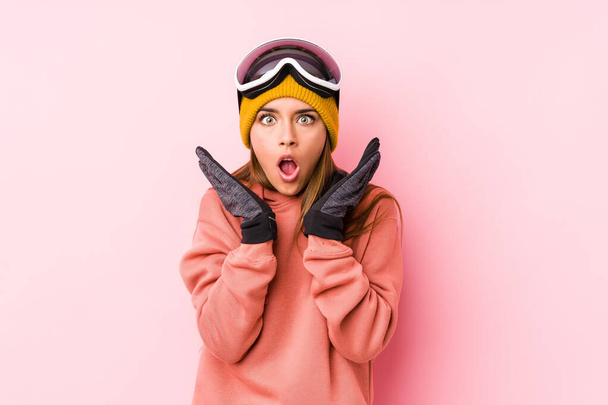 Jovem caucasiana vestindo uma roupa de esqui isolada surpreso e chocado
. - Foto, Imagem