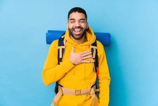 Jonge Arabische reiziger backpacker man geïsoleerde lacht luid houden hand op de borst. - Foto, afbeelding