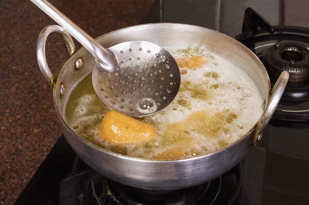 Pakoras siendo frito en una sartén en una estufa
 - Foto, Imagen