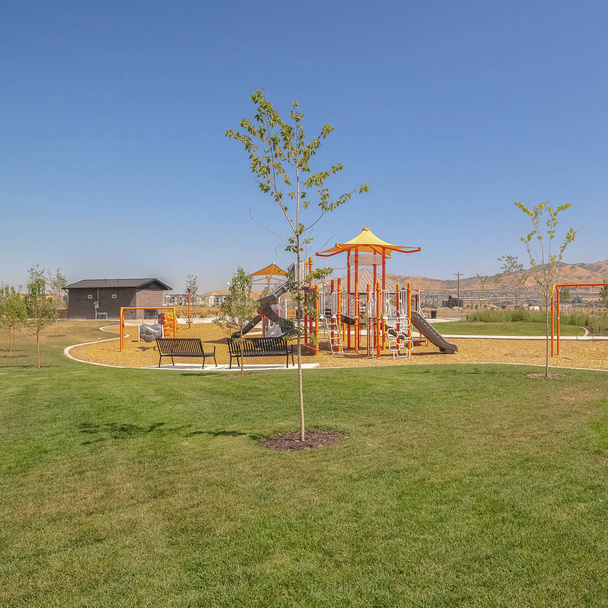 Quadro quadrado Parque cênico com mesas de piquenique e bancos e playground contra o céu azul
 - Foto, Imagem