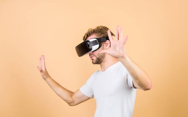Explore cyber space. Man hipster virtual reality headset on peach background. Entertainment and education. Virtual communication. Virtual simulation. Man play game in VR glasses. Augmented 3D world - 写真・画像