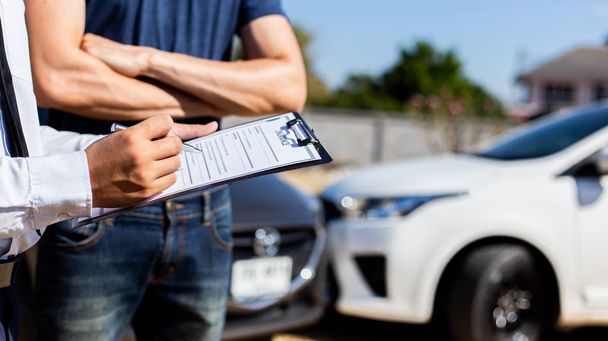 保険募集人は、自動車事故による損害賠償を請求するために道路上で衝突した自動車の損害を検査し、保険の概念. - 写真・画像