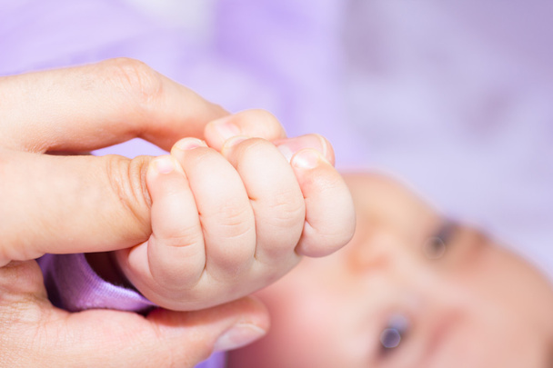 Bebé atrapando el dedo de la madre
 - Foto, imagen