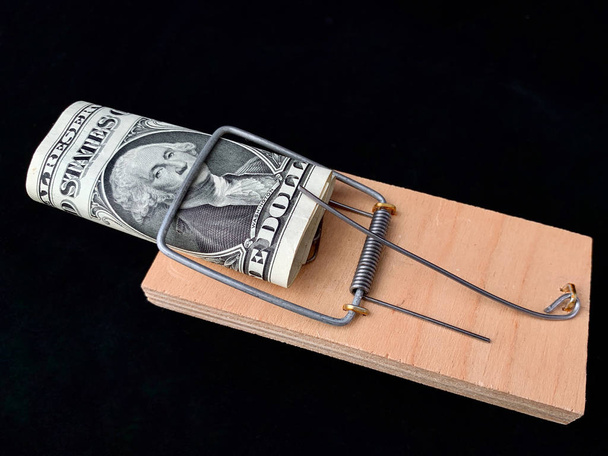Dólares en una ratonera sobre un fondo negro. Trampa de madera con cebo y mecanismo para ratas y ratones. Concepto: la felicidad no es dinero, la codicia
 - Foto, Imagen