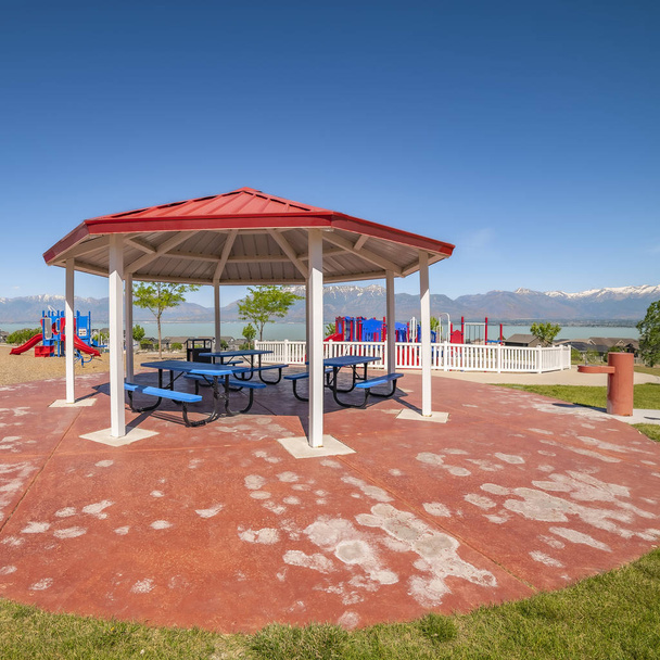 Quadro quadrado pavilhão de piquenique em forma de octógono com vista para o parque infantil colorido e lago cênico
 - Foto, Imagem