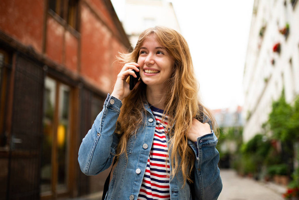 笑顔の若い女性の肖像画は、都市の外で携帯電話と話して - 写真・画像
