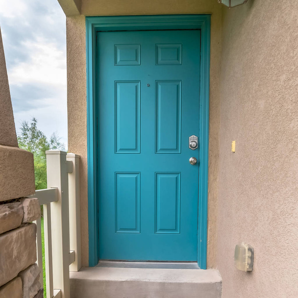 quadratische Nahaufnahme des Hauseingangs mit blaugrüner Haustür und Betonaußenwand - Foto, Bild