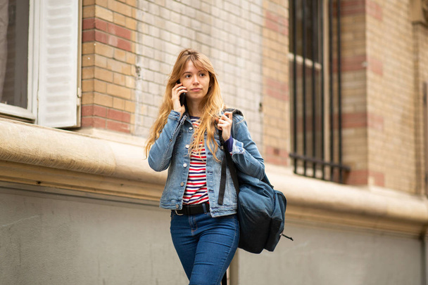 Ritratto di studentessa universitaria che cammina e parla con il cellulare all'esterno
 - Foto, immagini