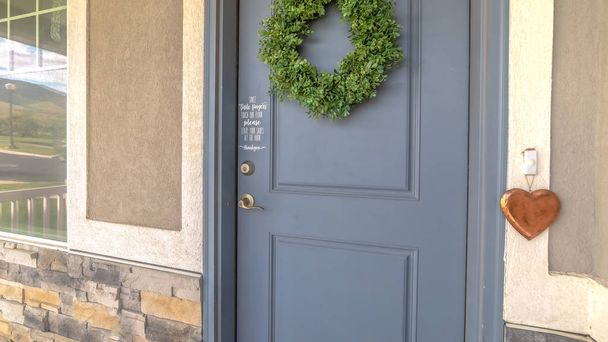 Pano Home exetrior met close-up op blauw grijze voordeur versierd met groene krans - Foto, afbeelding