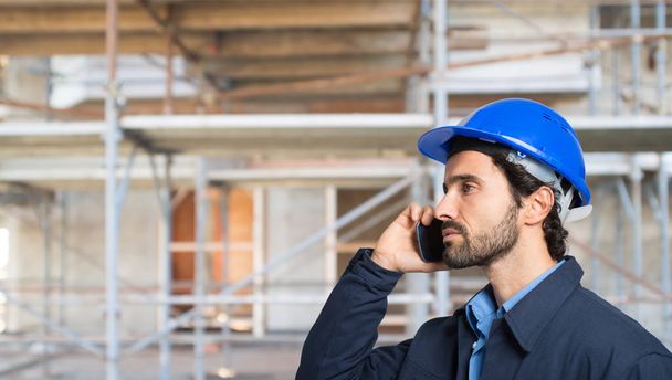 Portrait of a worker talking on the phone in a construction site - Fotó, kép