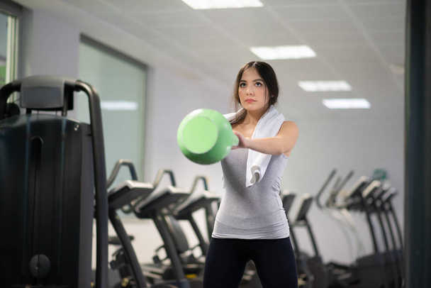 Woman training in a gym using a kettlebell ball - Photo, image