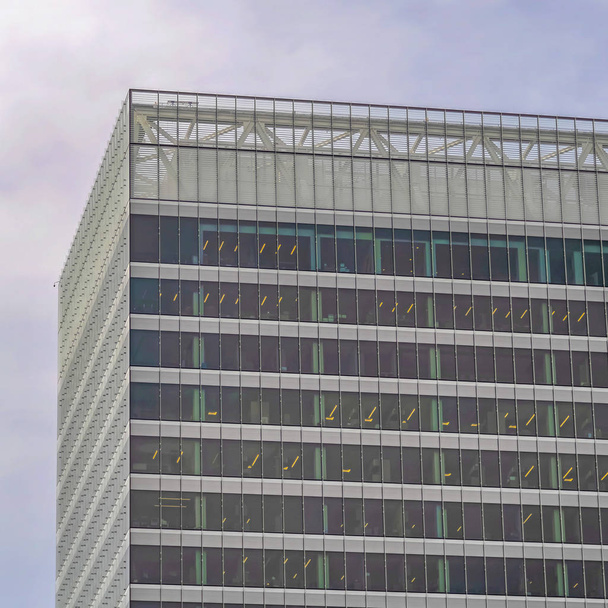 Vierkant frame Modern commercieel gebouw exterieur met hoge glazen ramen tegen bewolkte lucht - Foto, afbeelding
