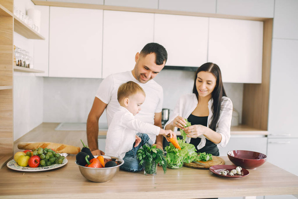 Família prepara a salada em uma cozinha
 - Foto, Imagem