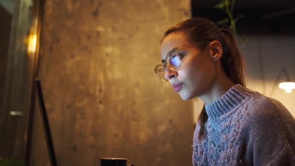 mulher jovem freelancer sentado à noite no café e usando laptop, olhando para o monitor
 - Filmagem, Vídeo