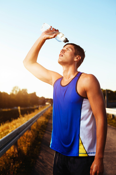 Athlete drinking after workout. - Фото, изображение