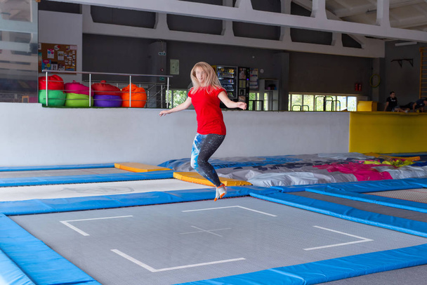 Fitness, hauska, vapaa-ajan ja urheilutoiminnan käsite - nuori onnellinen nainen hyppää trampoliinilla sisätiloissa
 - Valokuva, kuva