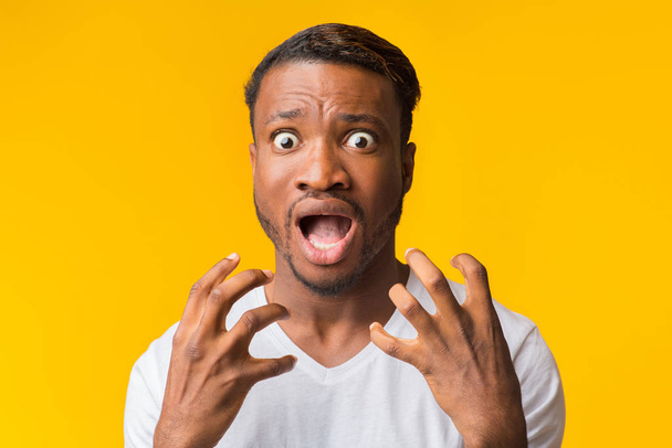 Vyděšený Afro chlap křičící za ruce blízko obličeje, žluté pozadí - Fotografie, Obrázek