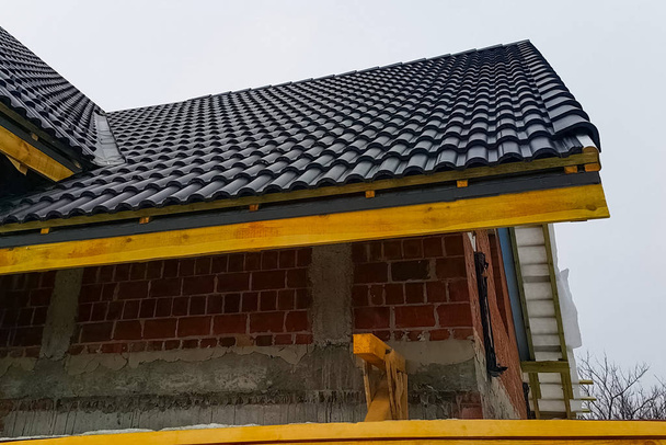 Εγκατάσταση της οροφής του σπιτιού από κεραμικά μαύρα πλακίδια. - Φωτογραφία, εικόνα