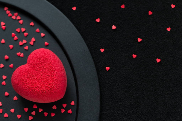 День святого Валентина концепция. Красное сердце бархатный торт на черном фоне со многими мини-конфеты в форме маленьких сердец
 - Фото, изображение