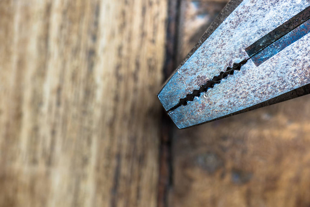 Old metall rusty pliers on a wooden worktop. Carpenter tools.  - Foto, afbeelding