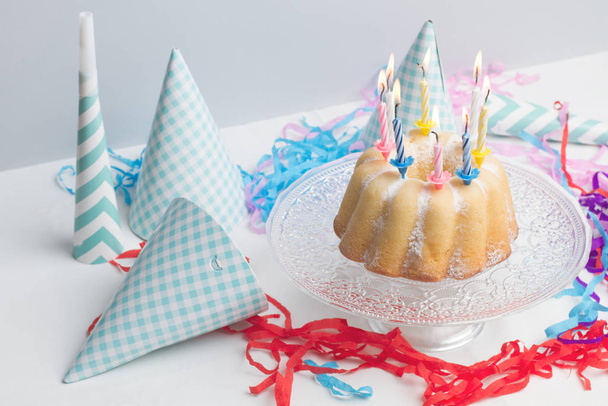 Een verjaardagstaart met gekleurde brandende kaarsen - Foto, afbeelding