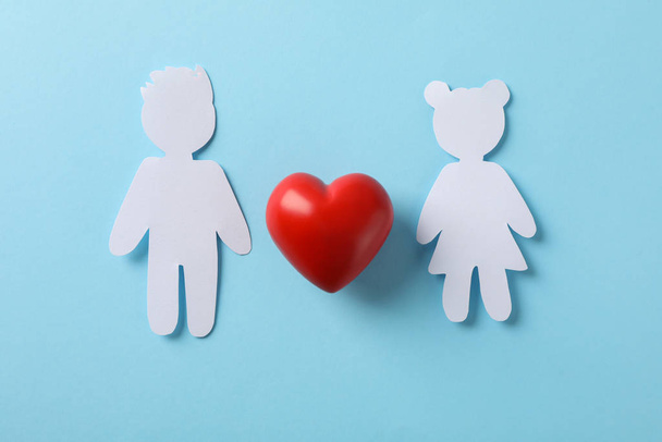 Figuras de menino e menina, e coração decorativo em fundo azul
 - Foto, Imagem