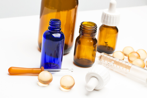Orvosi palackok cseppekkel a fehér asztalon - Fotó, kép