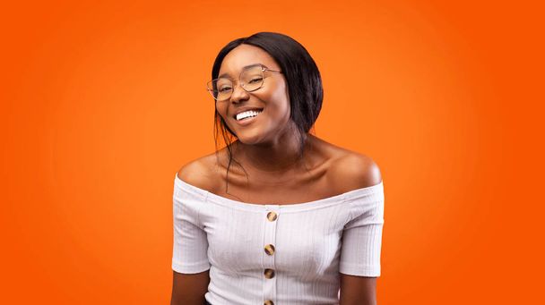 Африканська американська дівчина, яка посміхається, коли позаду помаранчевого фону (панорама) - Фото, зображення