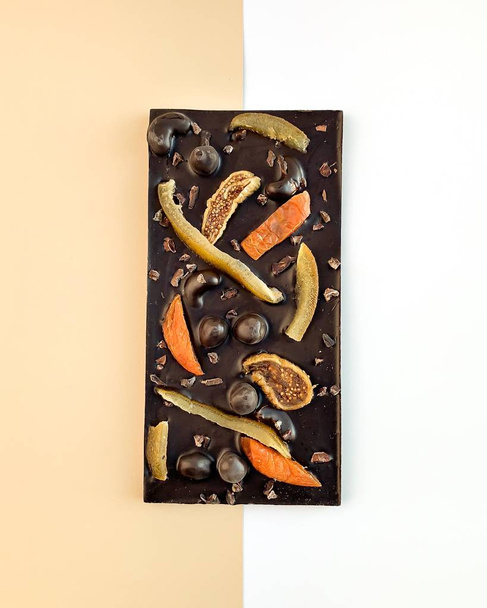 Chocolate with candied fruit and nuts on white beige background - Valokuva, kuva