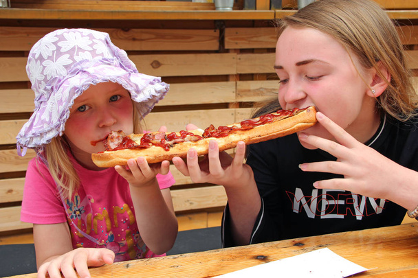 Dos chicas comen un sándwich grande al mismo tiempo
. - Foto, imagen