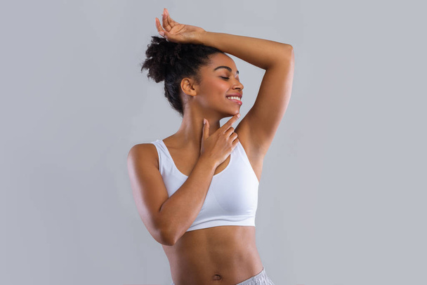 Happy afro girl smelling her armpit over grey background - Photo, Image