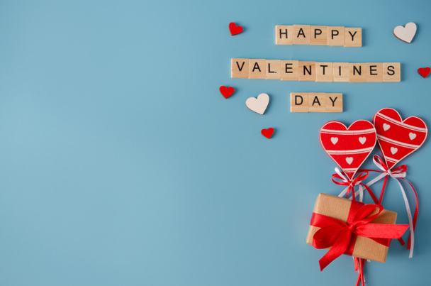 Tarjeta de felicitación de San Valentín. Inscripción Feliz día de San Valentín, caja de regalo y corazones de madera sobre fondo azul
. - Foto, Imagen
