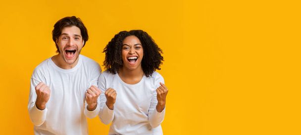 alegre pareja multirracial regocijando el éxito, levantando puños con emoción
 - Foto, imagen