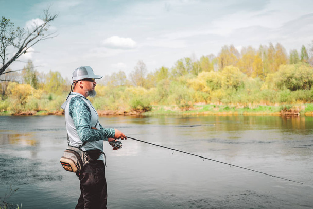 Pescador con una caña giratoria pescando en un río
  - Foto, imagen