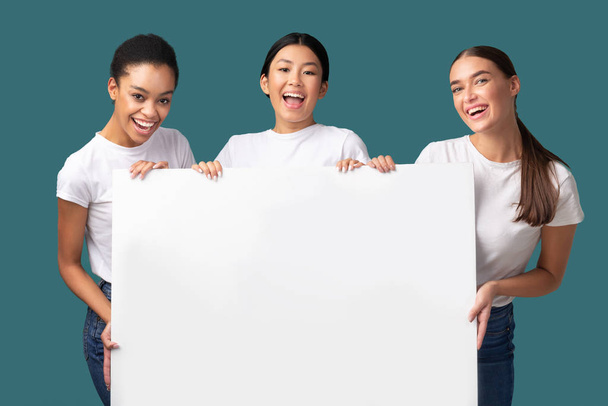 Três meninas multirraciais segurando placa em branco em pé no estúdio, Mockup
 - Foto, Imagem