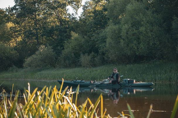 Fisherman swims on a kayak on the river. - Fotografie, Obrázek