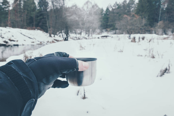 Buvez le thé d'un thermos sur une rivière d'hiver
. - Photo, image