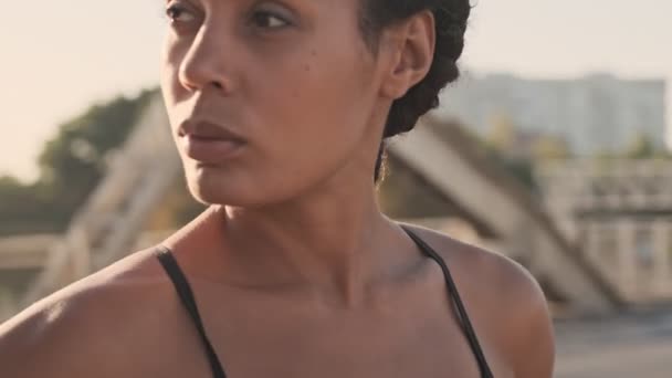 Cropped view of focused african american nice woman looking aside while working out on old bridge - Materiał filmowy, wideo