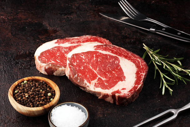 Syrové čerstvé maso Ribeye Steak, koření a masové vidličky na rustikální b - Fotografie, Obrázek