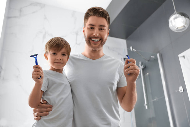 Dad and son with razors in bathroom, low angle view - Фото, изображение