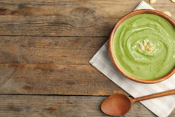Delicious broccoli cream soup served on wooden table, flat lay. Space for text - Zdjęcie, obraz