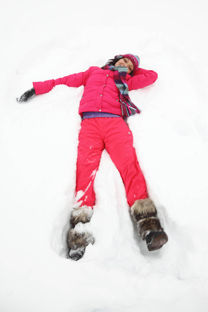 Young woman laying down on snow - Fotó, kép