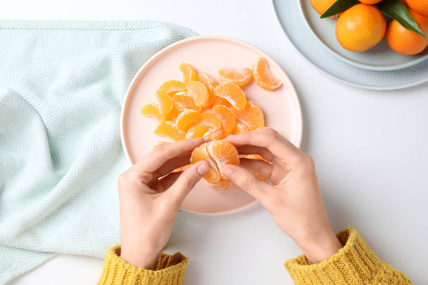 Woman holding fresh juicy tangerine at white table, top view - Fotografie, Obrázek