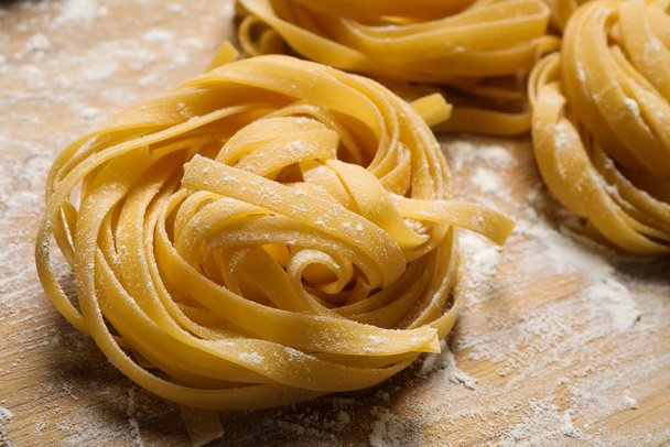 Tagliatelle pasta on wooden board, closeup view - 写真・画像