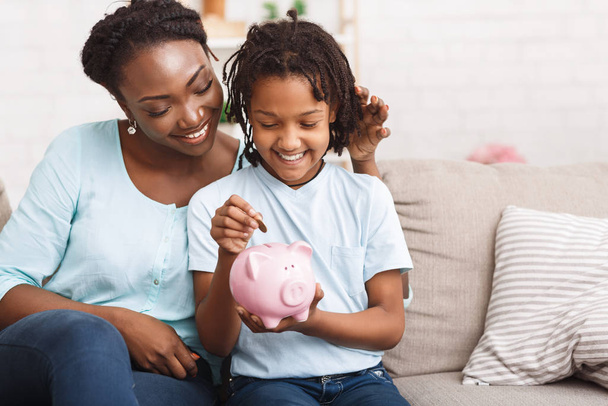African american family inserting money to piggybank - Photo, Image