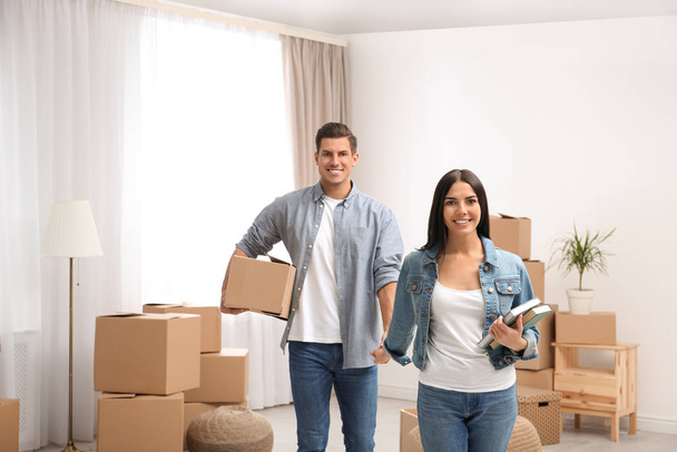 Happy couple in room with cardboard boxes on moving day - Foto, imagen